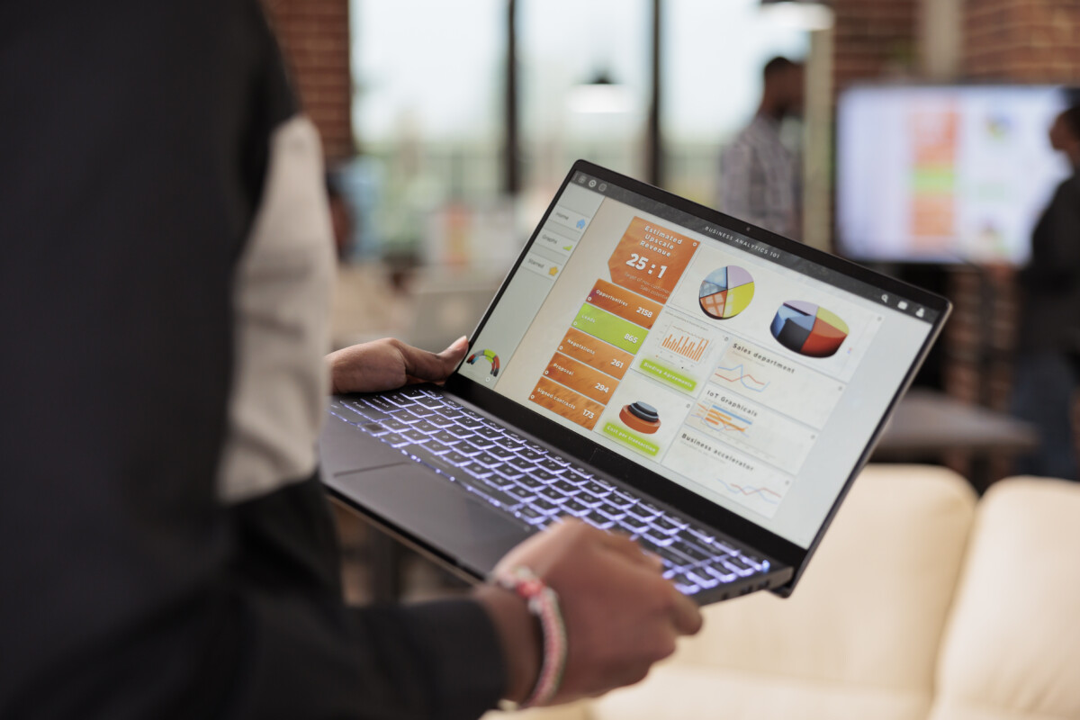 Employee holding laptop with business diagrams