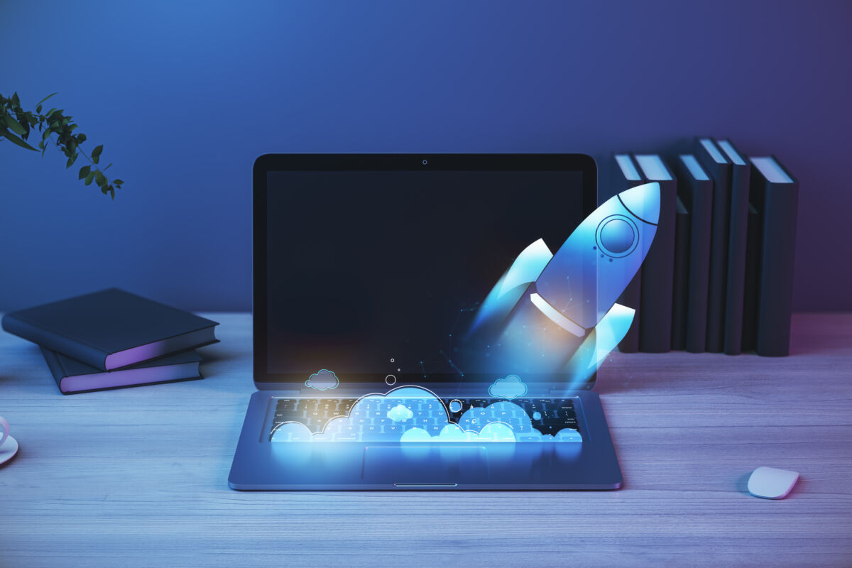 Close up of laptop at workplace with supplies and glowing flying blue rocket. Start up and launch concept. 3D Rendering.
